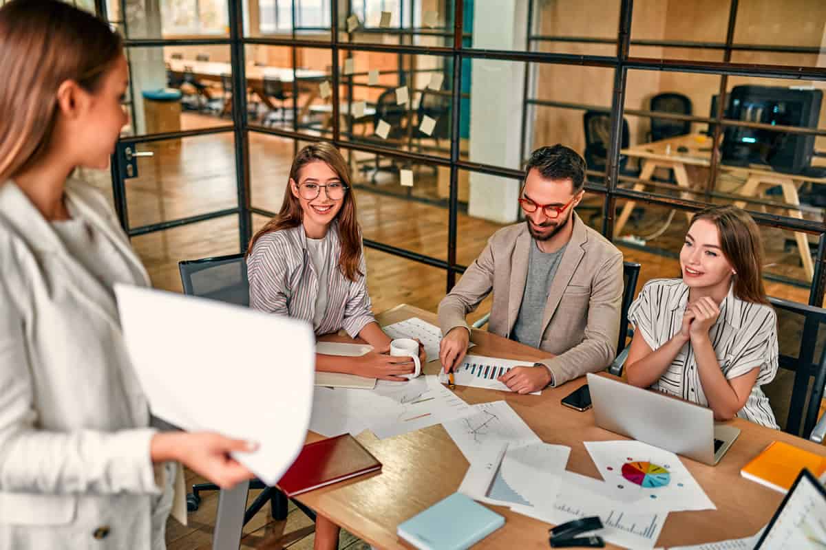 Un grupo de personas sentadas alrededor de una mesa en una oficina, discutiendo estrategias de SEO para agencias de marketing.