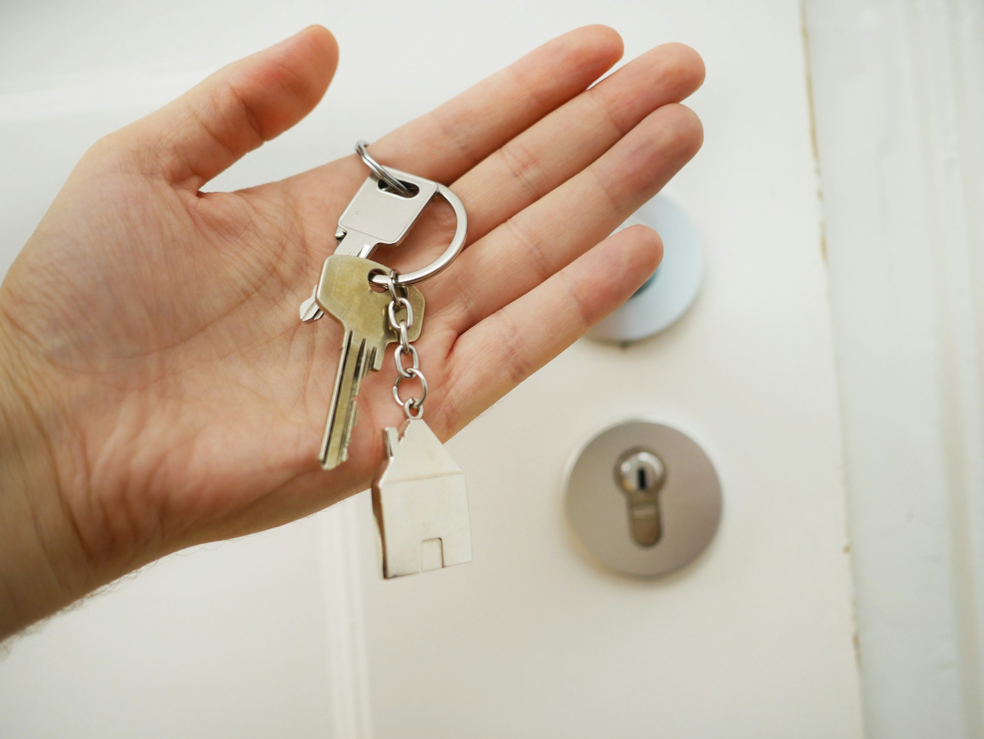 Una mano que sostiene un juego de llaves con un llavero con forma de casa frente a la cerradura de una puerta, que simboliza cuán efectivo el SEO para inmobiliarias puede abrir puertas para aumentar la visibilidad en línea.